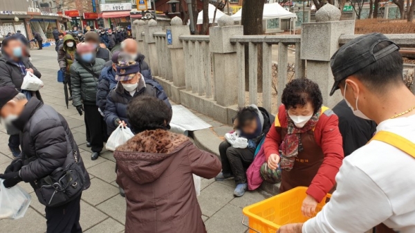 지난 15일 탑골공원 북문에서 도시락을 나눠 주는 원각사 무료급식소 후원자와 자원봉사자들.